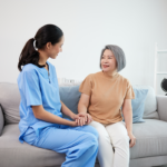 Woman in scrubs with patient on sofa