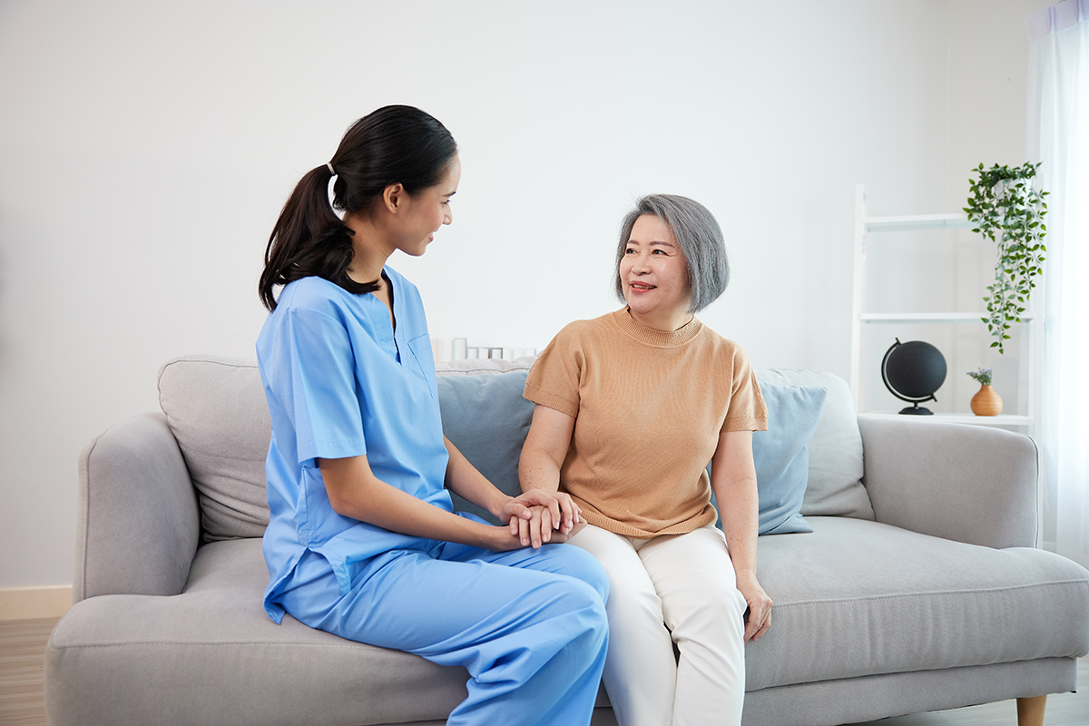 Woman in scrubs with patient on sofa